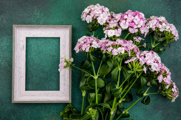 Vista dall'alto del telaio grigio con fiori rosa chiaro su una superficie verde