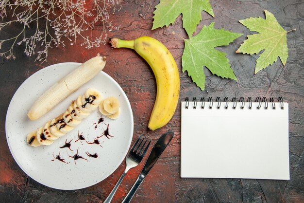 Vista dall'alto deliziosa banana con pezzi affettati all'interno del piatto sullo sfondo scuro