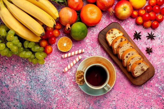 Vista dall'alto deliziosa composizione di frutta con torte a fette e tazza di tè sulla superficie rosa