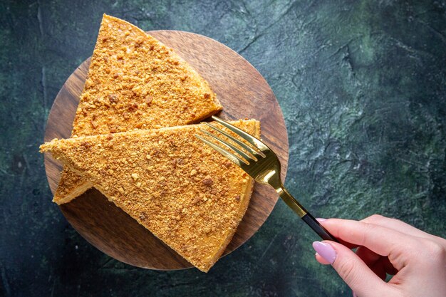 Vista dall'alto deliziosa fetta di torta di miele di esso sulla superficie scura tavola di legno rotonda