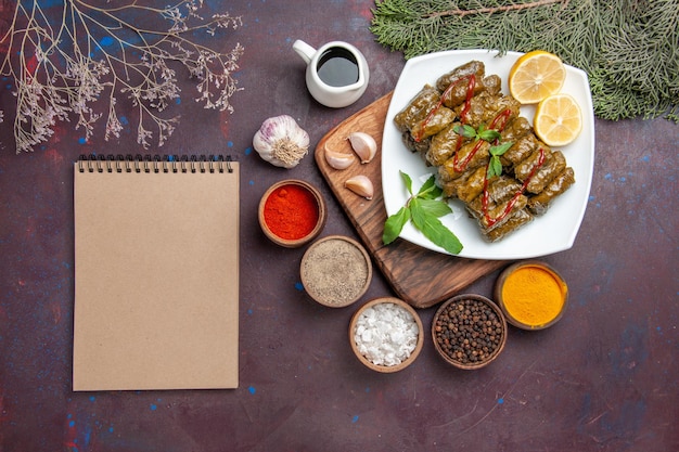 Vista dall'alto deliziosa foglia dolma con fette di limone e condimenti sullo sfondo scuro piatto di carne foglia cena pasto cibo