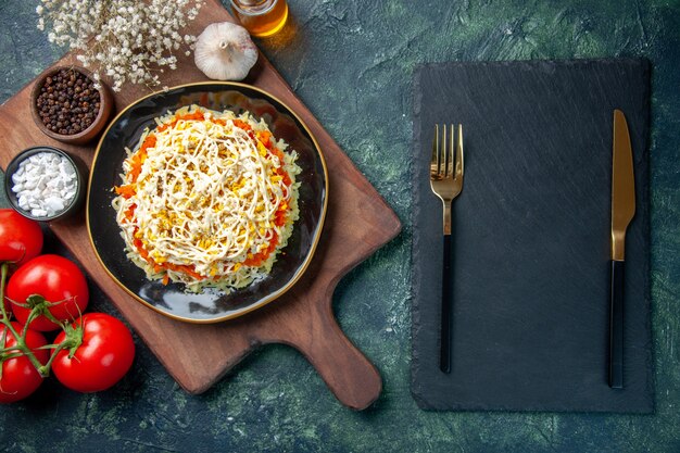vista dall'alto deliziosa insalata di mimosa all'interno del piatto con pomodori rossi su sfondo blu scuro