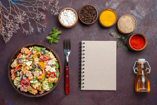 Vista dall'alto deliziosa insalata di verdure con condimenti diversi su sfondo scuro pranzo dietetico per insalata di verdure salutari