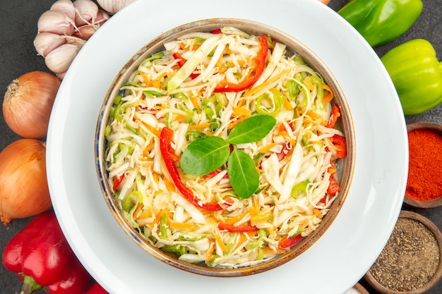 Vista dall'alto deliziosa insalata di verdure con condimenti e verdure fresche sullo sfondo grigio