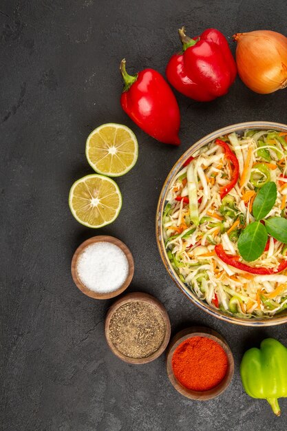 Vista dall'alto deliziosa insalata di verdure con condimenti e verdure fresche sullo sfondo grigio