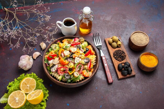 Vista dall'alto deliziosa insalata di verdure con fette di limone e insalata verde su uno sfondo scuro pasto dietetico insalata salutare