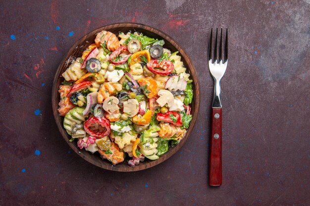 Vista dall'alto deliziosa insalata di verdure con pomodori, olive e funghi su sfondo scuro spuntino per il pranzo di verdure dell'insalata di salute