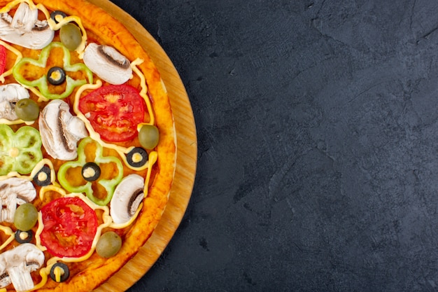 Vista dall'alto deliziosa pizza ai funghi con pomodori rossi peperoni olive e funghi tutti affettati all'interno sulla scrivania scura cibo pasto pizza