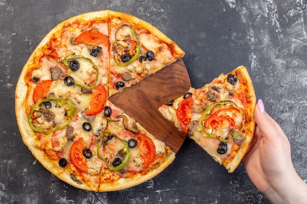 Vista dall'alto deliziosa pizza al formaggio affettata e servita per donna su superficie grigia