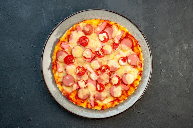 Vista dall'alto deliziosa pizza al formaggio con salsicce e pomodori su sfondo scuro cibo italiano torta di pasta fast-food foto colore