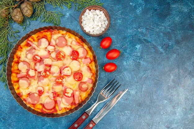 Vista dall'alto deliziosa pizza al formaggio con salsicce e pomodori sullo sfondo blu torta di pasta alimentare foto a colori fast-food italiano