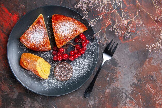 Vista dall'alto deliziosa torta a fette con bacche rosse sulla torta dolce da tavola scuro