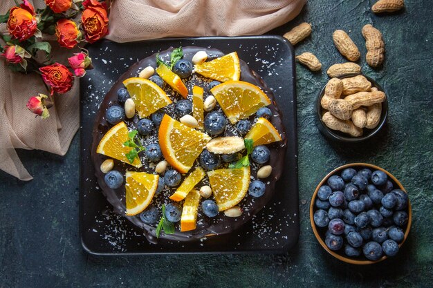 Vista dall'alto deliziosa torta al cioccolato con frutta fresca su fondo scuro