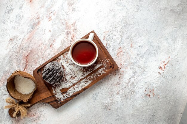 Vista dall'alto deliziosa torta al cioccolato con una tazza di tè su sfondo bianco torta al cioccolato biscotto zucchero dolce biscotto tè