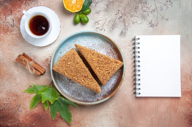 Vista dall'alto deliziosa torta al miele con una tazza di tè accesa