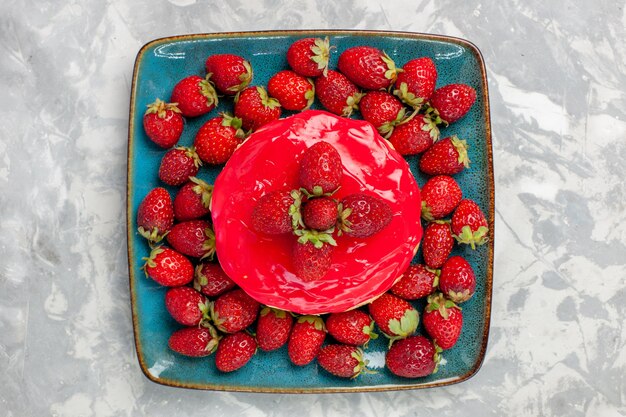 Vista dall'alto deliziosa torta alla ricerca piccola torta con crema rossa e fragole fresche sulla superficie bianca torta biscotto cuocere la crema zucchero dolce