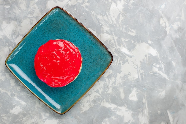 Vista dall'alto deliziosa torta alla ricerca piccola torta con crema rossa su sfondo bianco chiaro torta biscotto cuocere la crema zucchero dolce