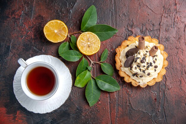 Vista dall'alto deliziosa torta cremosa con una tazza di tè sul dessert dolce della torta della tavola scura