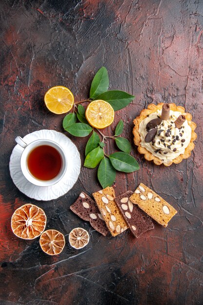 Vista dall'alto deliziosa torta cremosa con una tazza di tè sul dessert torta dolce tavolo scuro