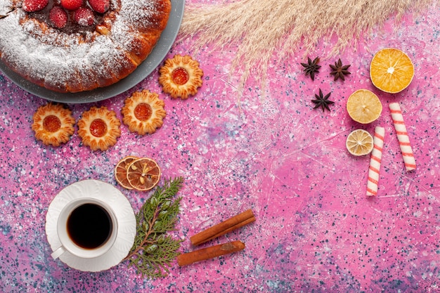 Vista dall'alto deliziosa torta di fragole con biscotti e tazza di tè sulla torta di sfondo rosa torta di biscotti di zucchero dolce