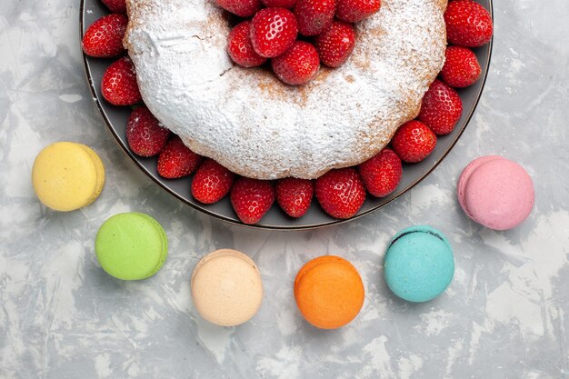 Vista dall'alto deliziosa torta di fragole con macarons francesi su bianco