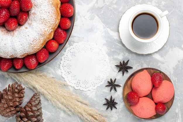 Vista dall'alto deliziosa torta di fragole con una tazza di tè su bianco