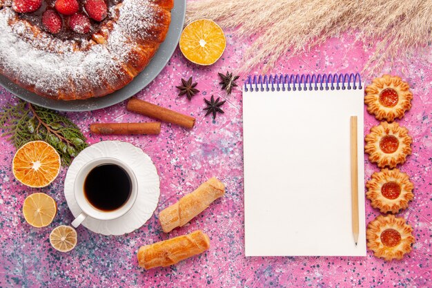 Vista dall'alto deliziosa torta di fragole torta di zucchero a velo con i biscotti e la tazza di tè sulla torta da scrivania rosa dolce zucchero biscotto torta biscotti