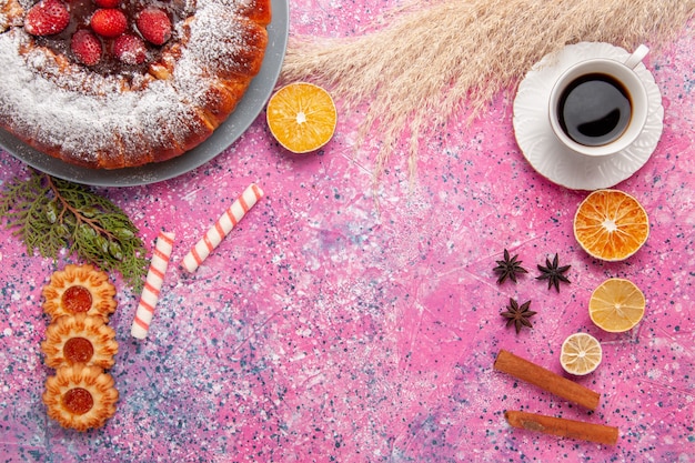 Vista dall'alto deliziosa torta di fragole torta di zucchero a velo con piccoli biscotti e tazza di tè sulla torta rosa scrivania torta di biscotti di zucchero dolce