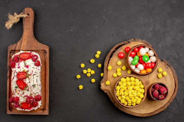 Vista dall'alto deliziosa torta fruttata con caramelle su uno sfondo scuro torta di zucchero candito pasta biscotto frutta