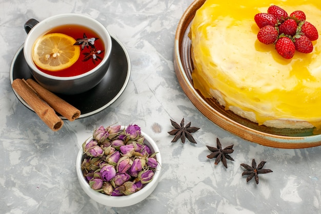 Vista dall'alto deliziosa torta fruttata con sciroppo giallo e tazza di tè sulla superficie bianca torta biscotto zucchero dolce cuocere il biscotto del tè