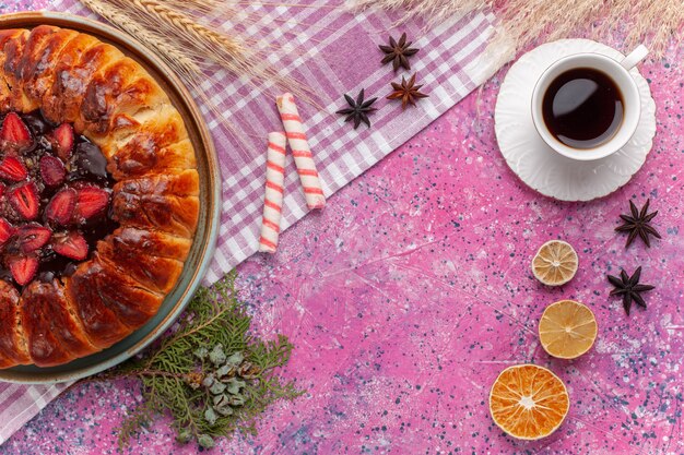 Vista dall'alto deliziosa torta fruttata torta di fragole con tazza di tè sul rosa