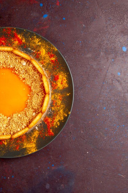 Vista dall'alto deliziosa torta gialla con biscotti e crema sulla superficie scura