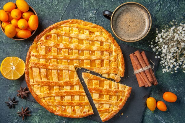 vista dall'alto deliziosa torta kumquat con un pezzo a fette e caffè su sfondo scuro