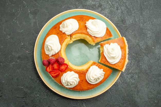 Vista dall'alto deliziosa torta rotonda affettata con crema bianca sullo sfondo grigio biscotto torta biscotto torta tè dolce