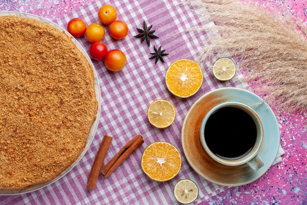 Vista dall'alto deliziosa torta rotonda all'interno del piatto con frutta e tè sulla torta da scrivania rosa brillante torta biscotto dolce cuocere