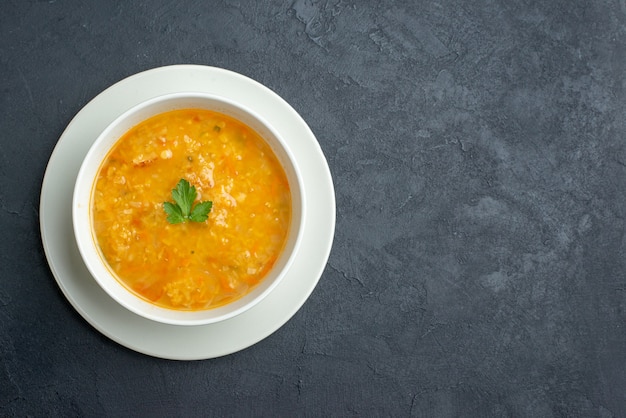 Vista dall'alto deliziosa zuppa all'interno del piatto bianco sulla superficie scura