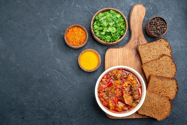 Vista dall'alto deliziosa zuppa con verdure e pane scuro su spazio grigio