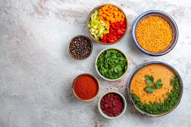 Vista dall'alto deliziosa zuppa di fagioli con diversi condimenti sulla verdura della zuppa di cibo pasto superficiale bianco