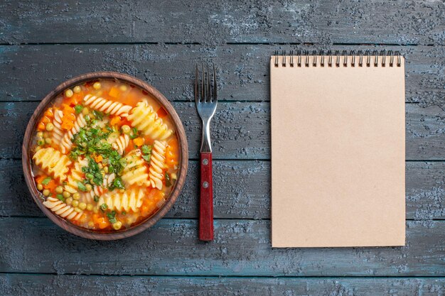 Vista dall'alto deliziosa zuppa di pasta da pasta italiana a spirale con verdure sul piatto da pranzo rustico scuro da tavolo salsa di zuppa di pasta italiana