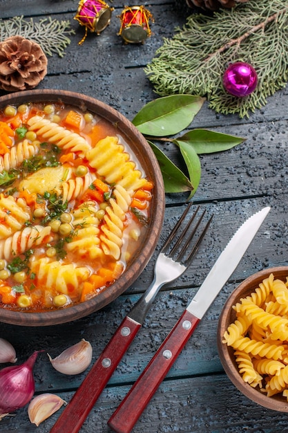 Vista dall'alto deliziosa zuppa di pasta dalla pasta italiana a spirale sul piatto da pavimento blu scuro cucina zuppa di colore pasta