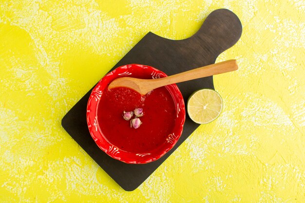 Vista dall'alto deliziosa zuppa di pomodoro con limone sulla tavola gialla, cibo vegetale di farina di minestra