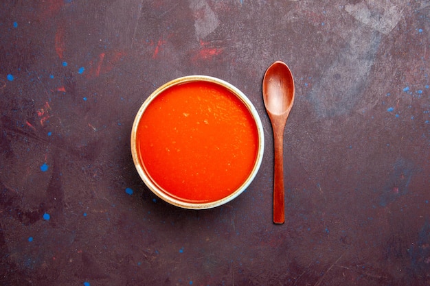 Vista dall'alto deliziosa zuppa di pomodoro cotta con pomodori freschi su fondo scuro