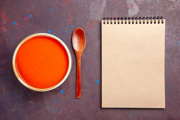 Vista dall'alto deliziosa zuppa di pomodoro cotta con pomodori freschi su fondo scuro