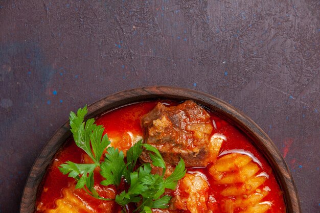 Vista dall'alto deliziosa zuppa di sugo di carne con verdure e patate a fette su un piatto da pranzo di cibo per zuppa di salsa scura da scrivania