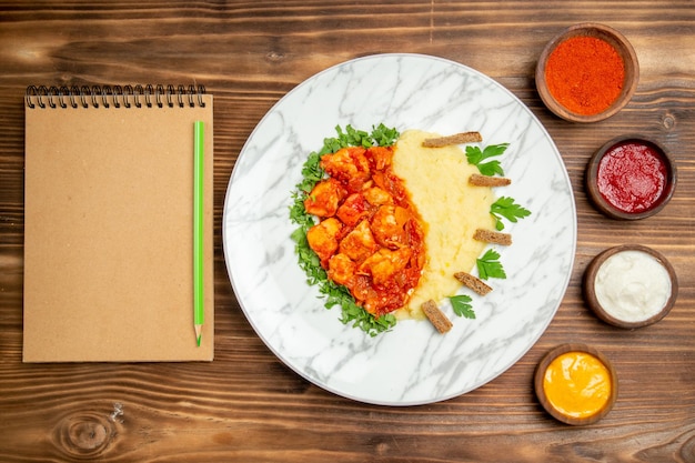 Vista dall'alto deliziose fette di carne con purè di patate e condimenti su scrivania in legno farina di pane a base di carne piatto di patate