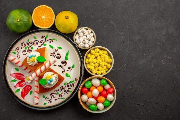 Vista dall'alto deliziose fette di torta con caramelle e mandarini freschi sullo sfondo scuro torta torta di biscotti dolci frutta