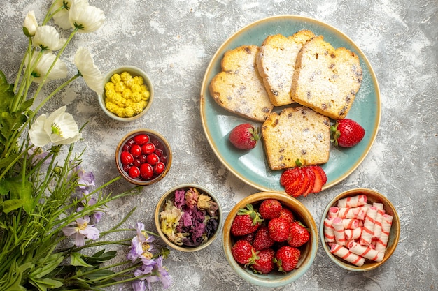 Vista dall'alto deliziose fette di torta con frutta e caramelle alla luce