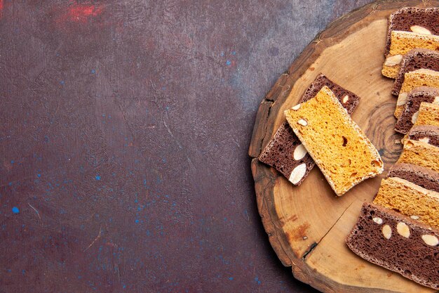 Vista dall'alto deliziose fette di torta con noci sullo sfondo scuro tè zucchero biscotti torta biscotto torta dolce