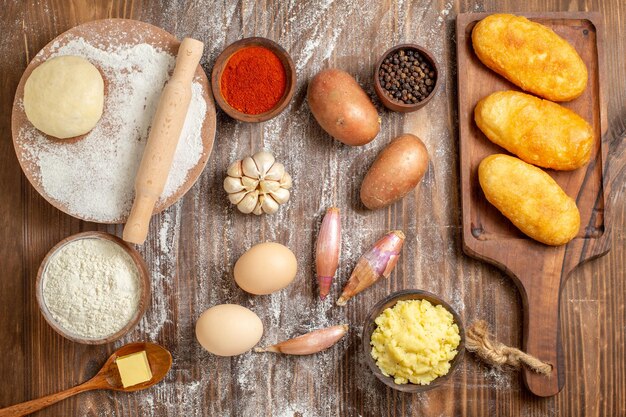 Vista dall'alto deliziose focacce di patate con condimenti e farina sulla scrivania in legno cuocere il colore della pasta di peperone torta