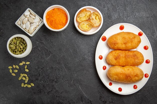 Vista dall'alto deliziose focacce di patate con ingredienti su una torta da scrivania grigio scuro